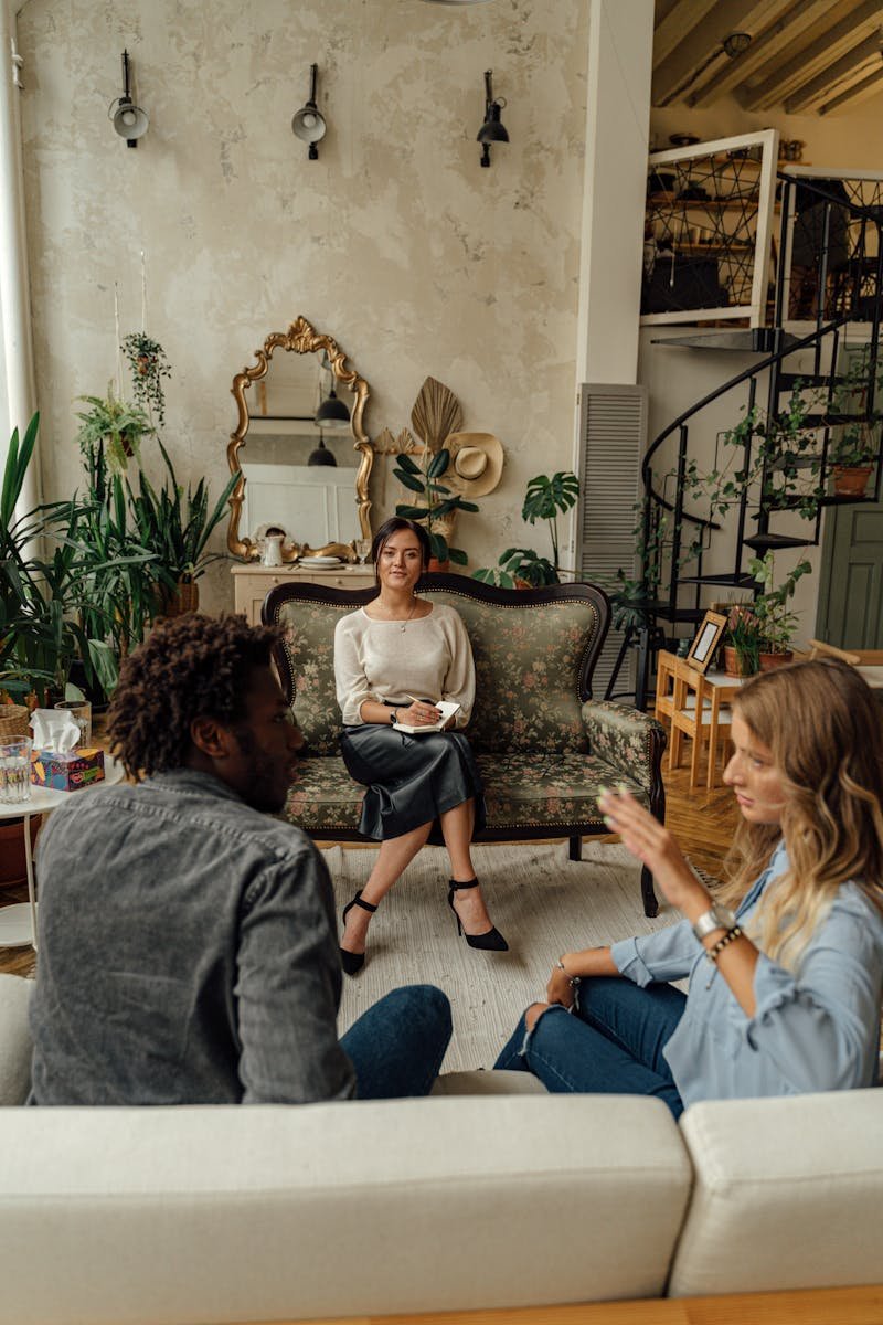 A therapy session with a couple and therapist in a stylish living room setting.